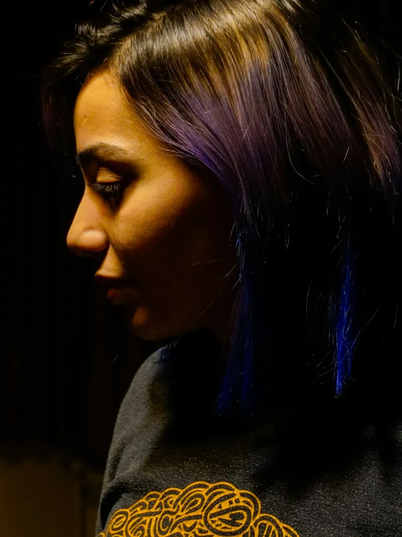 Frau mit violett gefärbten Haaren im schwachen Licht