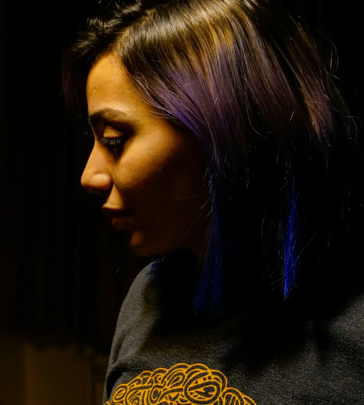 Frau mit violett gefärbten Haaren im schwachen Licht